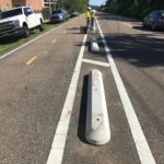 Crews installing curbing for the protected bike lane on Behrman Highway